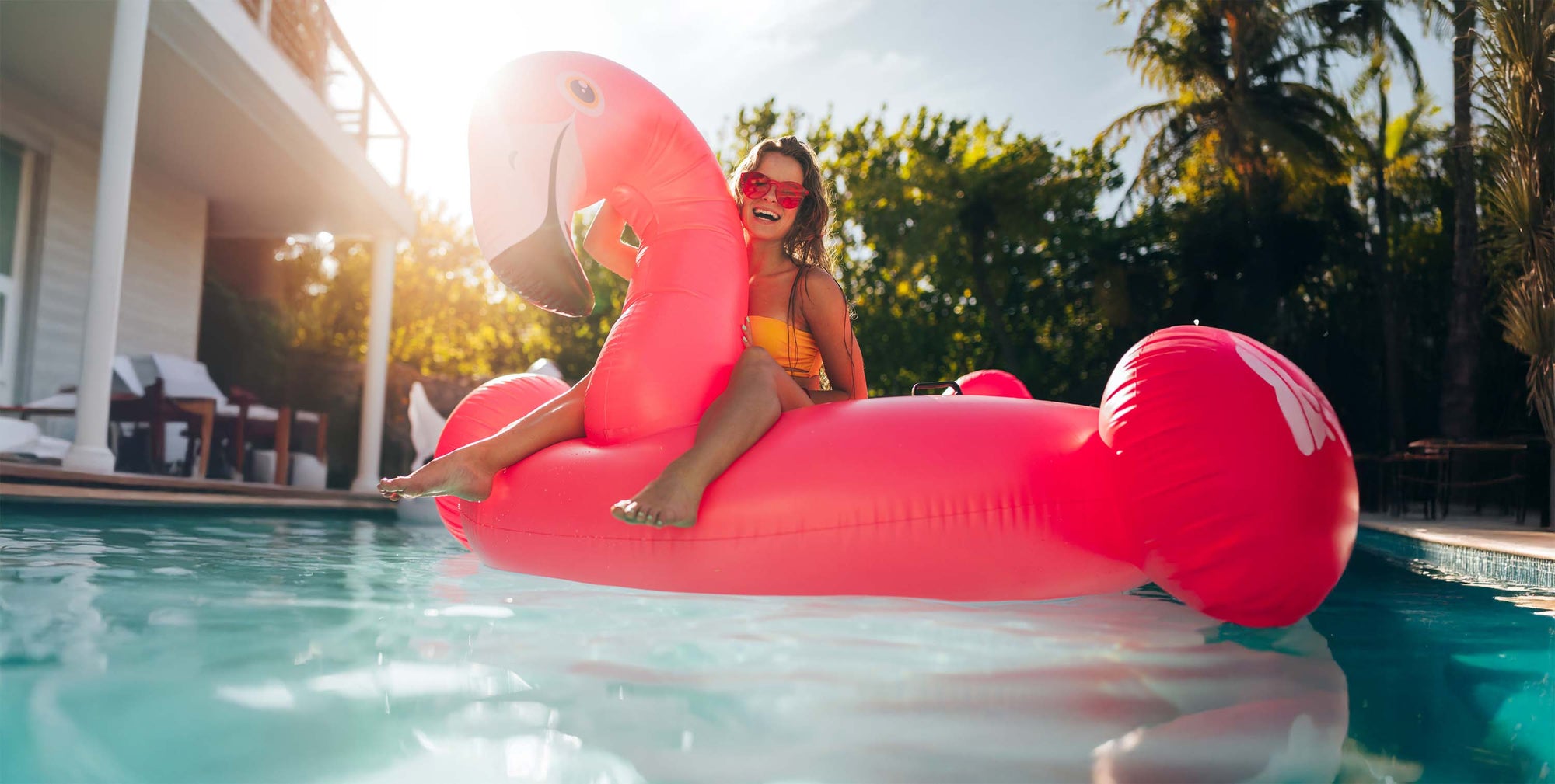 Women in a Pool riding a large inflatable Pink Flamingo Float